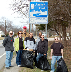 Sailors standing in front of Adopt a Road sign